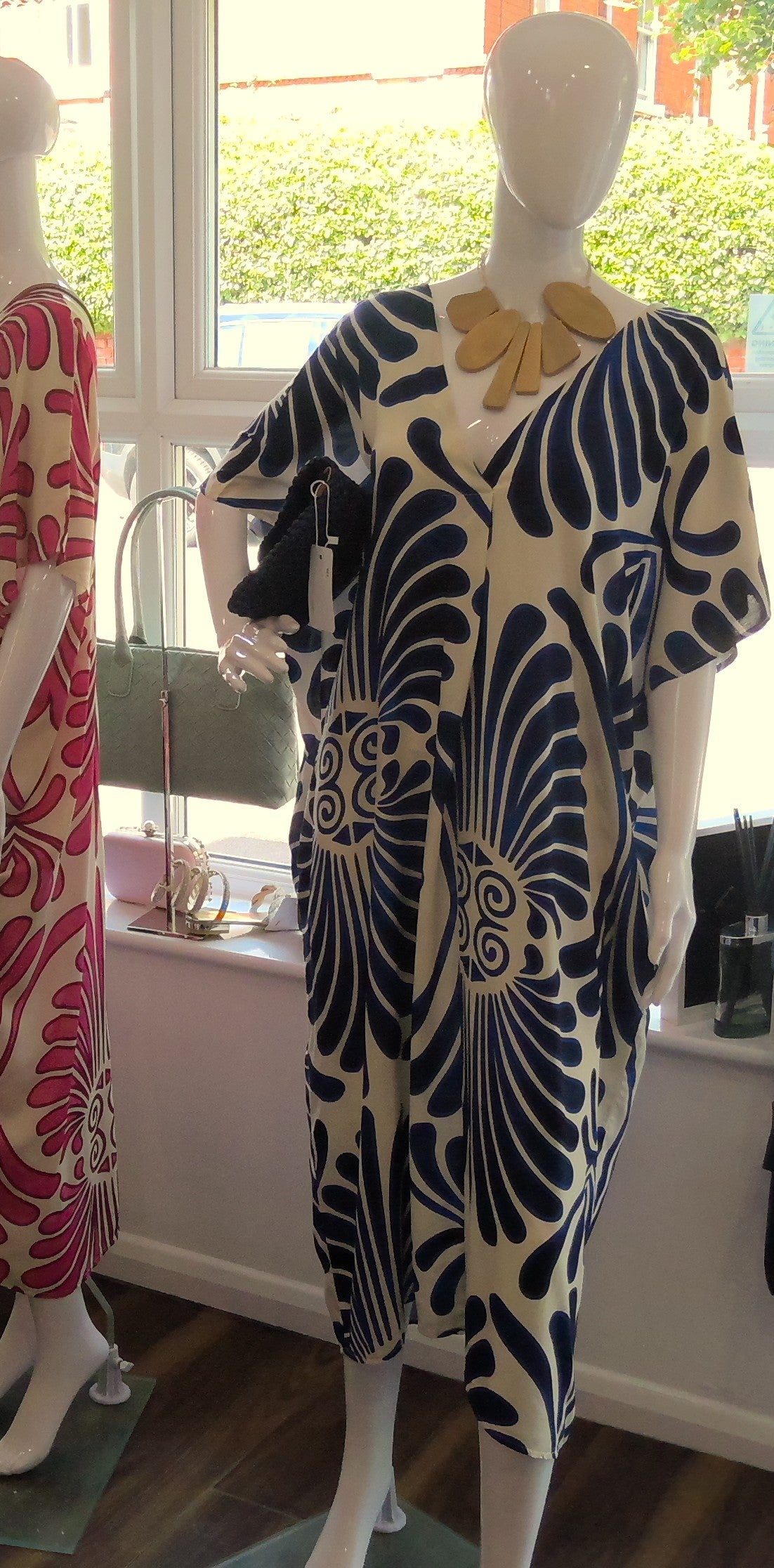 Mannequin wearing a blue and white abstract patterned dress in a store setting.