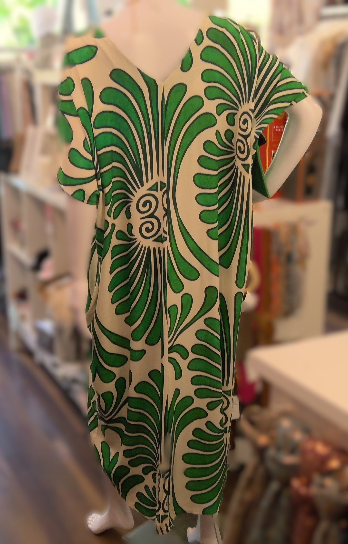 Mannequin wearing a green and white patterned dress in a store setting