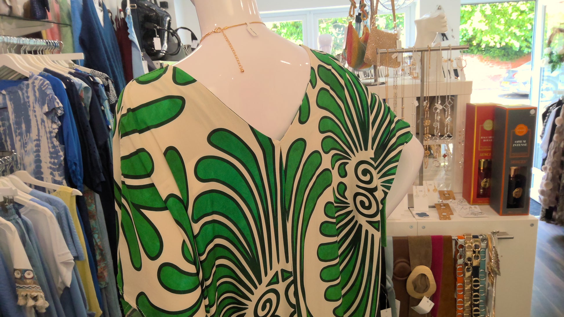 Mannequin wearing a green and white abstract patterned dress in a store setting