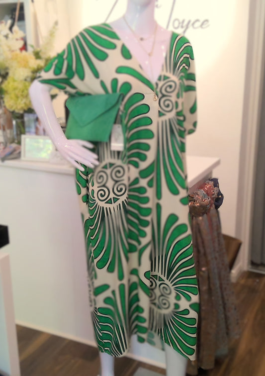 Mannequin wearing a green and beige abstract patterned dress with a blurred background